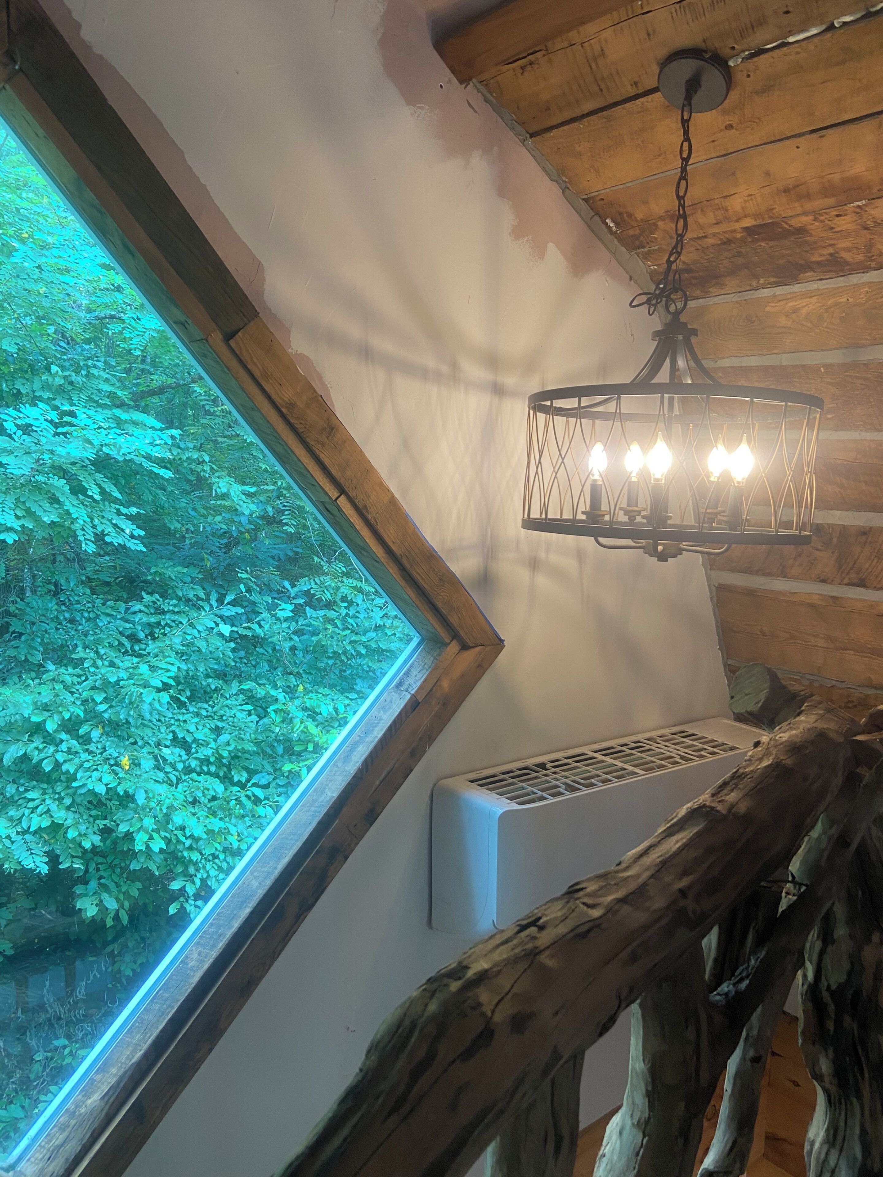 Ein Zimmer mit großem Fenster, Holzboden und einem Wandheizkörper.