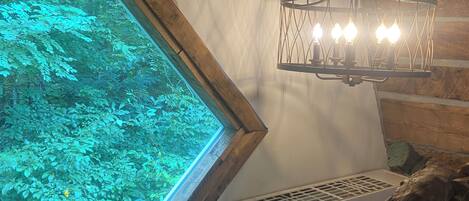 A room with a large window, a wooden ceiling, and a wall-mounted heater.