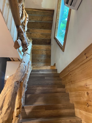 A wooden staircase with a rustic design, leading to an upper floor.