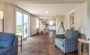 A spacious living area with a sofa, a dining table with chairs, and a kitchen in the background.