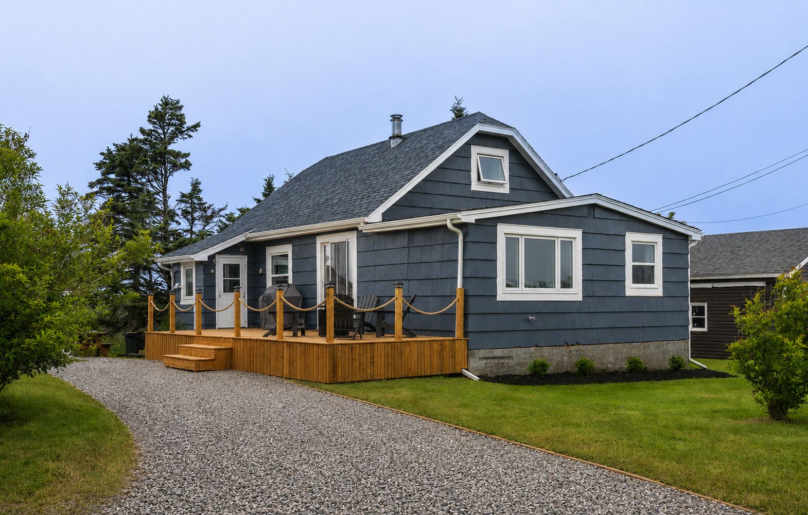 A house with a covered porch, a gravel driveway, and a fenced yard.
