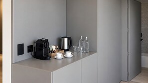 A modern kitchen with a coffee maker, kettle, cups, and glasses on a countertop. - Lev Hotel (Buenos Aires)