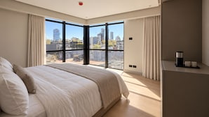 A modern bedroom with a large bed, a view of the cityscape through floor-to-ceiling windows, and a minimalist decor. - Lev Hotel (Buenos Aires)