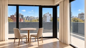 A modern room with a large window, a round table, two chairs, and a view of a cityscape. - Lev Hotel (Buenos Aires)