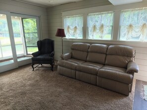 A room with a beige leather sofa, a dark armchair, and a floor lamp. - Glass-Front Lake Cottage, Fire Pit, Sleeps 7. Wireless internet, Heat/AC. (Horton)