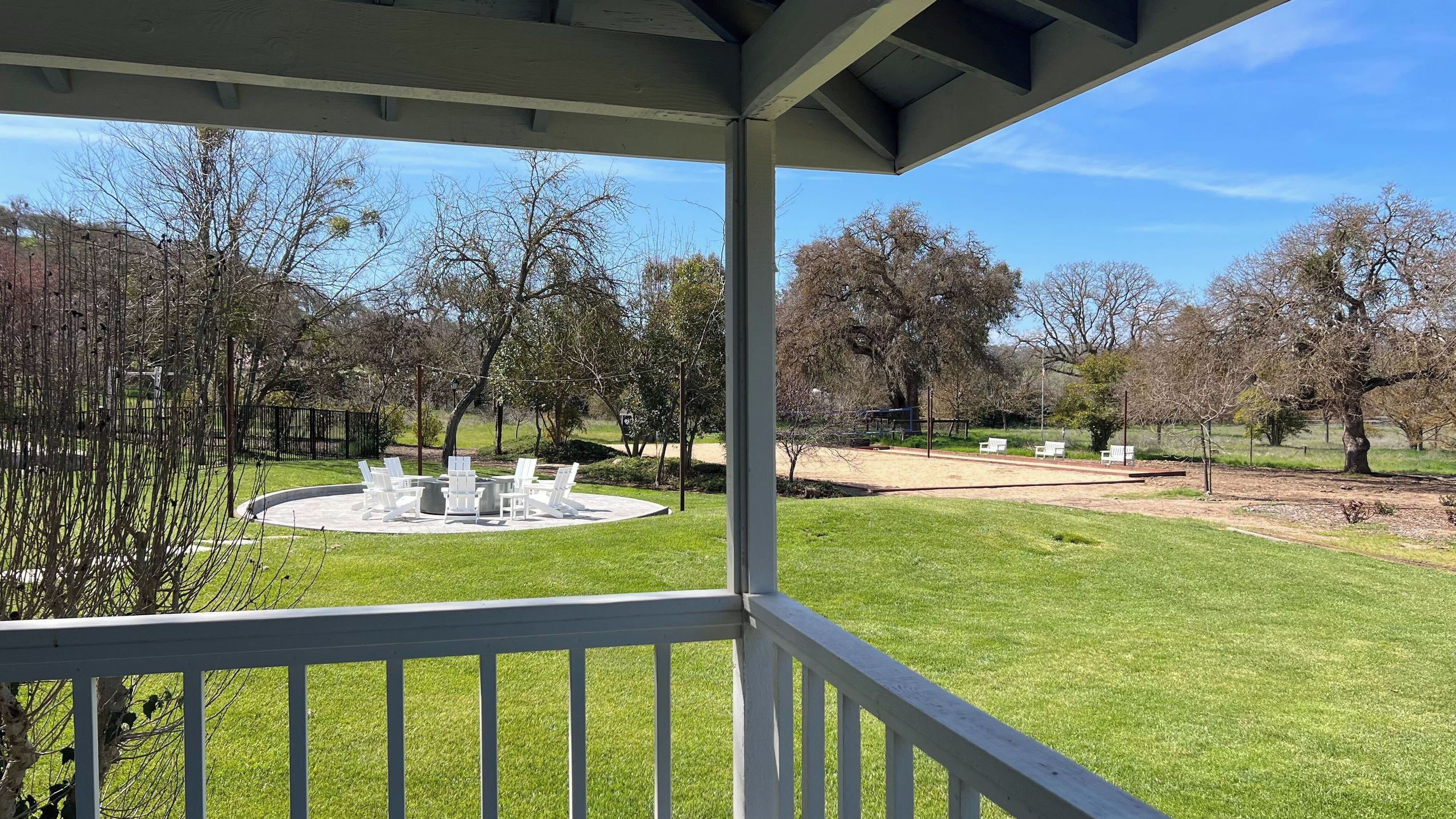 A covered outdoor area with a circular seating arrangement and a lawn.
