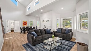 A spacious living room with a large sofa set, a glass coffee table, and a dining area with a table and chairs. - Oaks and Roses Ranch by Avantstay Pool + Game Room Paso Wine Country (Paso Robles)