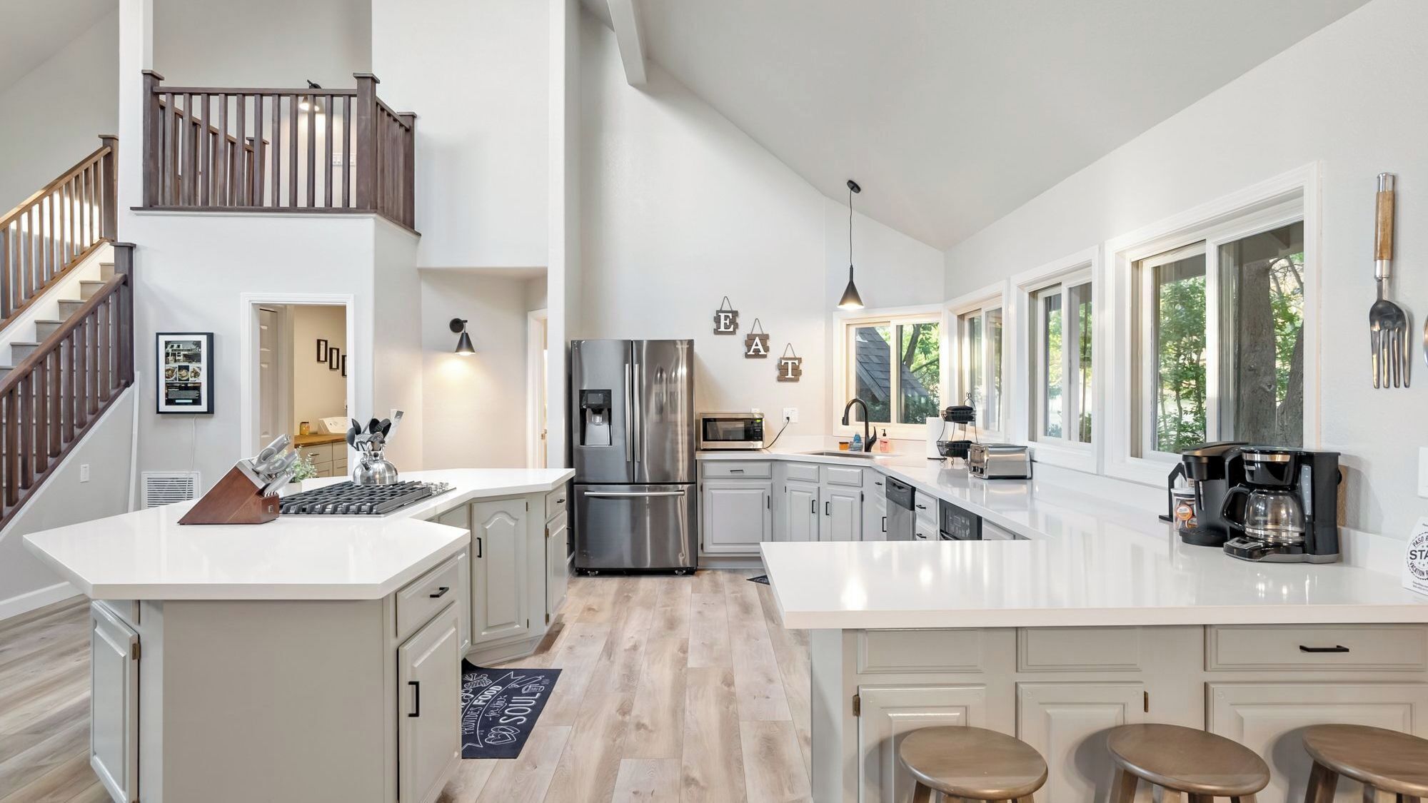 A spacious kitchen with a central island, stainless steel appliances, and a staircase leading to an upper level.