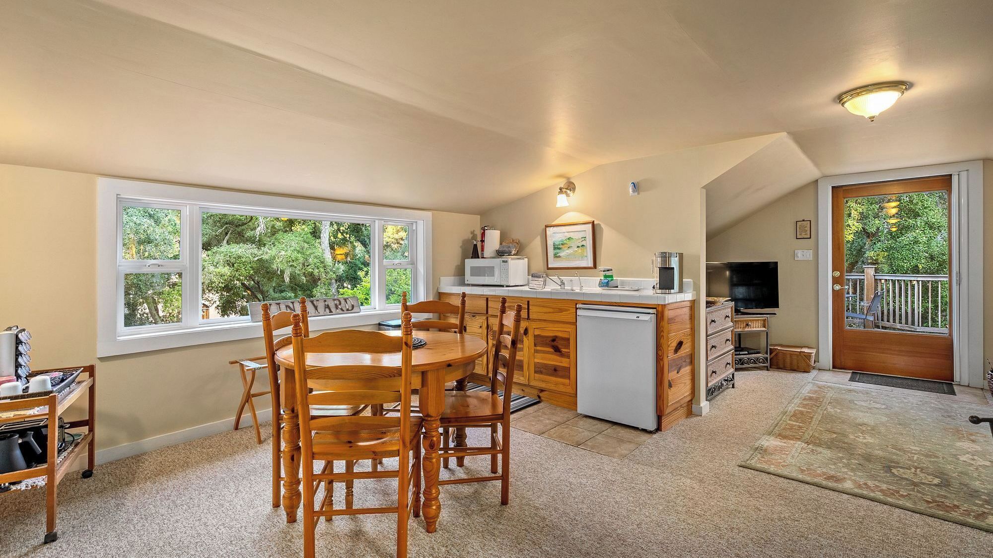 A compact kitchen with a dining area, a microwave, a refrigerator, and a television.