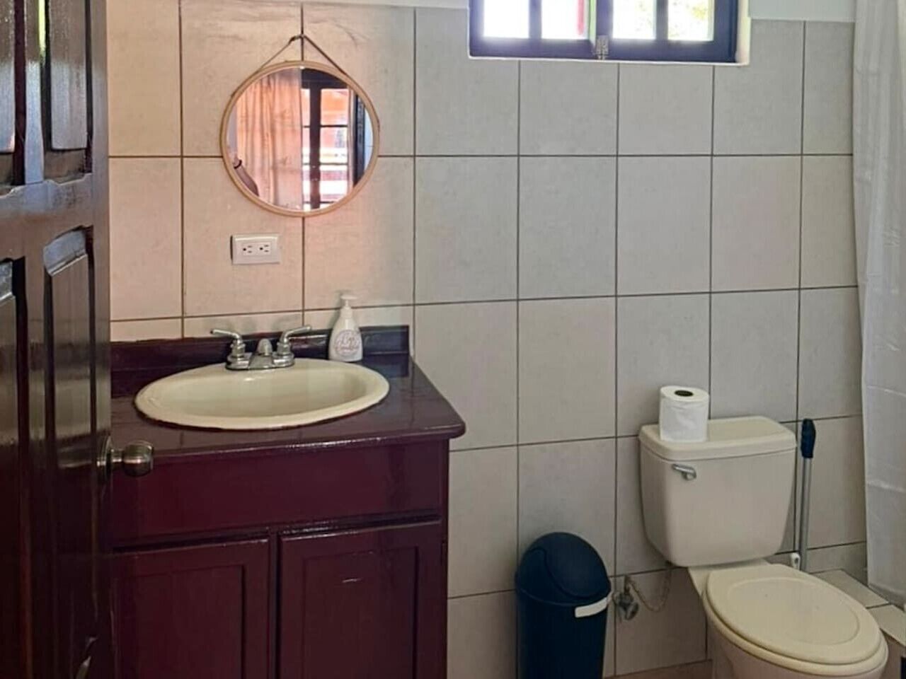 Kylpyhuone, jossa on pesuallas, peili, wc ja roskakori.