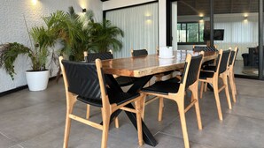 Ein moderner Essbereich mit Holztisch und -stühlen, Topfpflanzen und Blick ins Freie durch große Fenster.