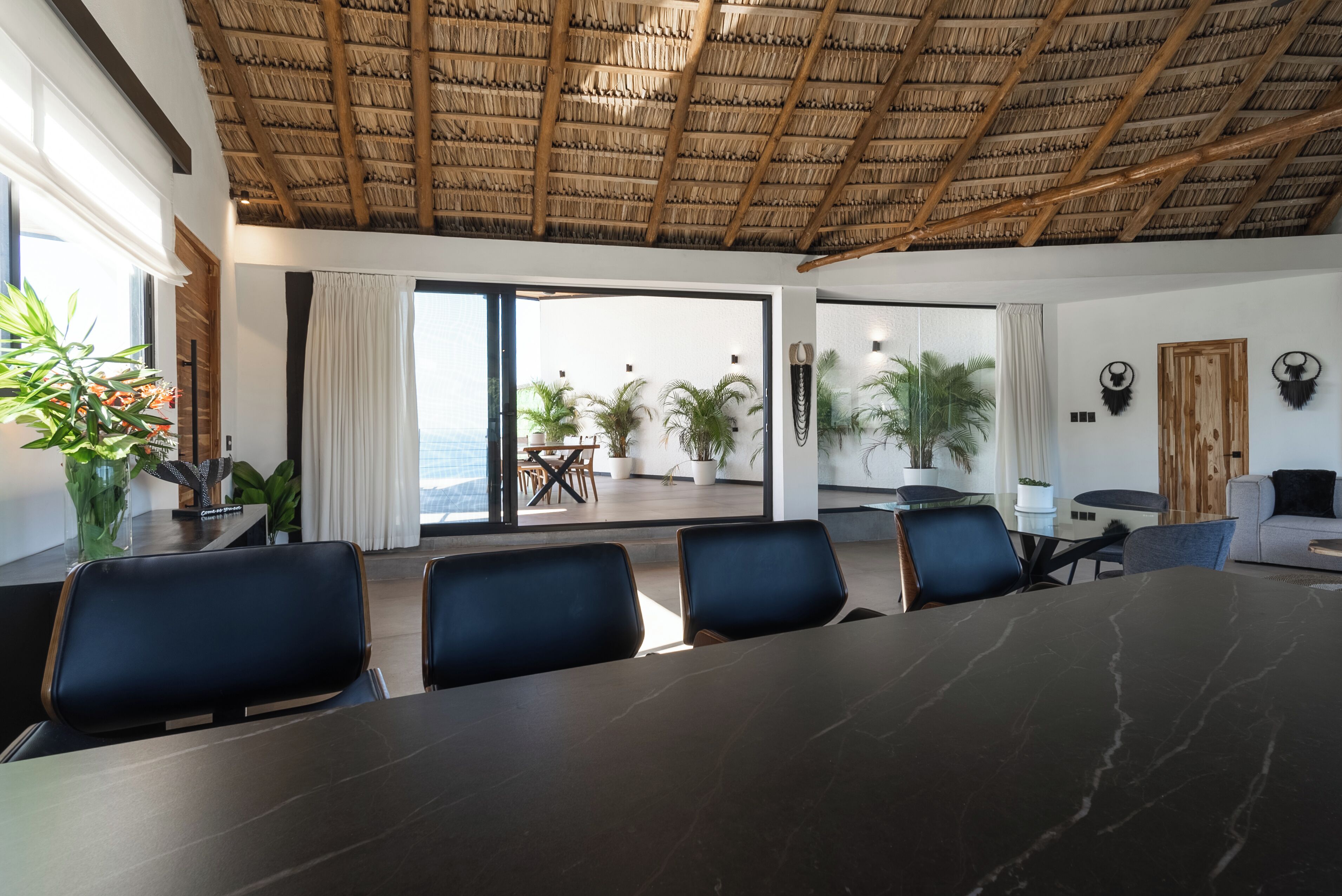 A conference room with a large table, several chairs, and a view of the outdoors through glass doors.