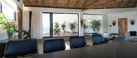 A conference room with a large table, several chairs, and a view of the outdoors through glass doors.