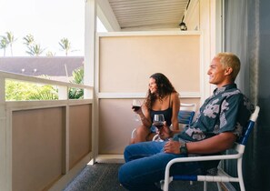 Un espace extérieur abrité, aménagé avec des sièges, d’où l’on peut admirer des palmiers et un bâtiment en arrière-plan.