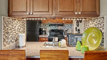 A kitchen with wooden cabinets, a black refrigerator, a microwave, a stove, and a sink.