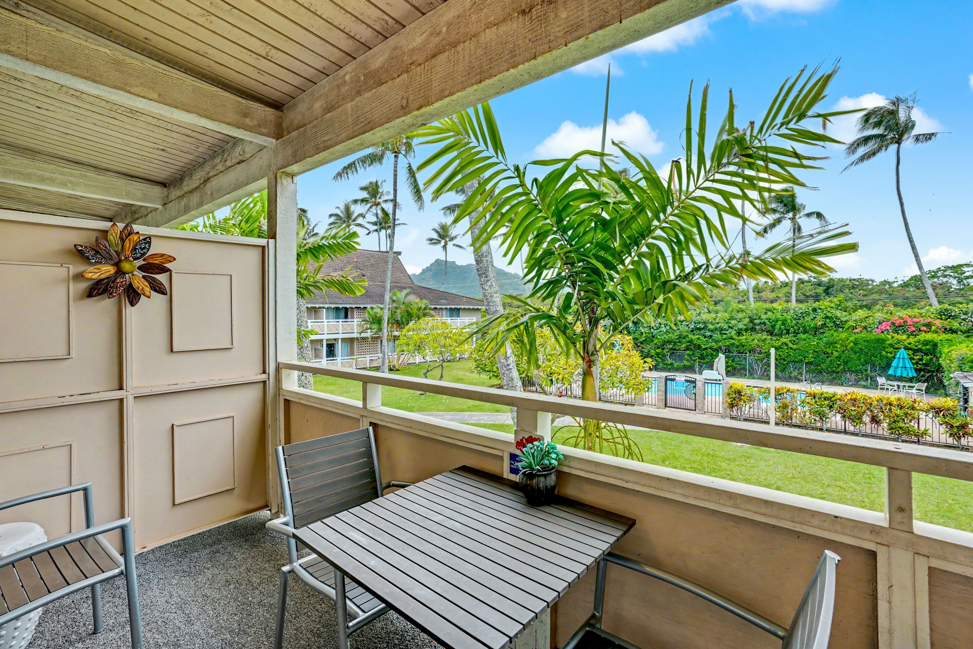 A balcony with a wooden ceiling, a metal table, and two metal chairs.