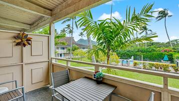 A balcony with a wooden ceiling, a metal table, and two metal chairs.