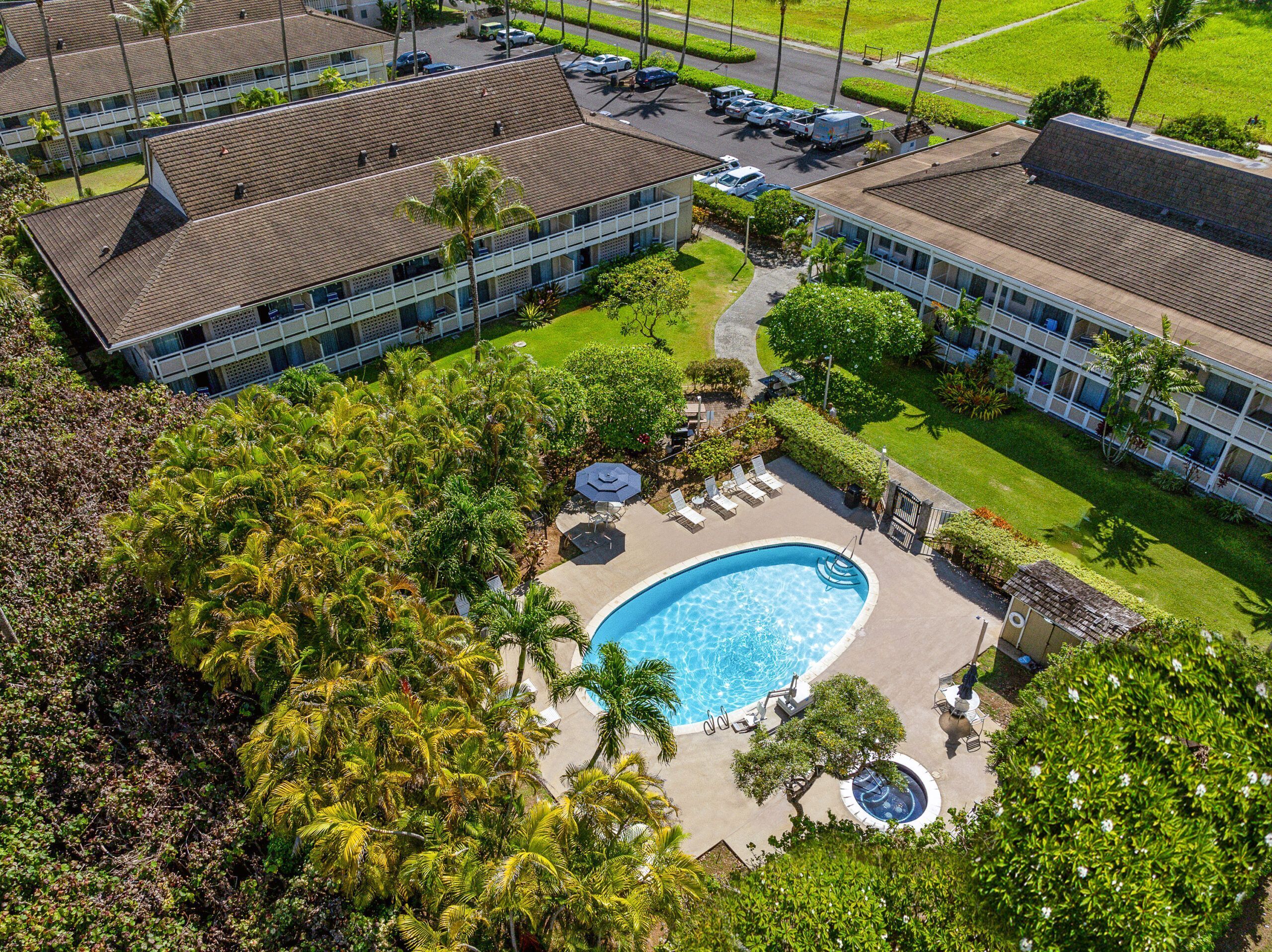 A hotel with a swimming pool, lounge chairs, and a well-maintained garden.
