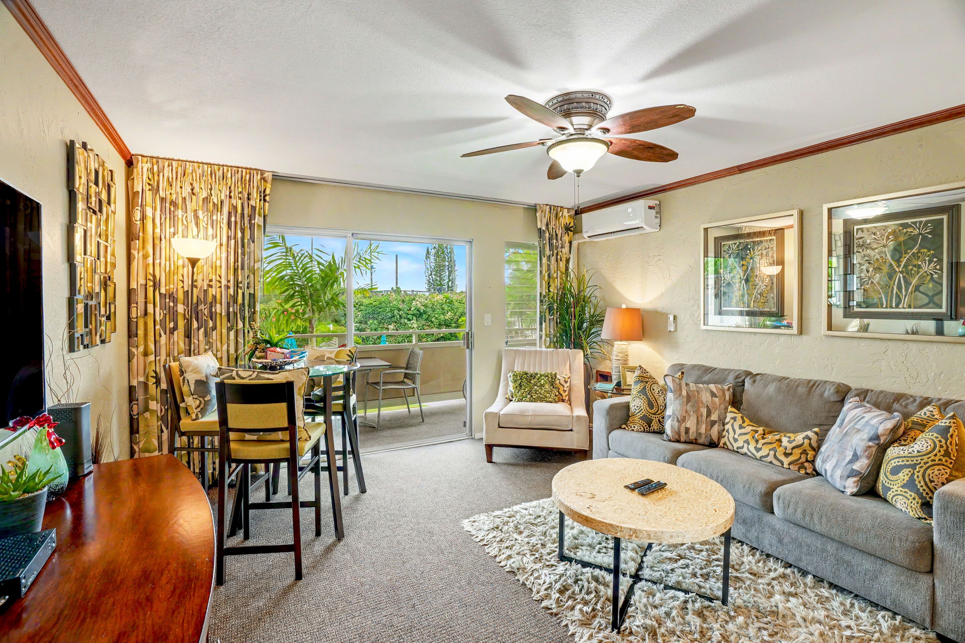 A spacious living area with a ceiling fan, a sofa, a coffee table, and a dining area with chairs and a table.