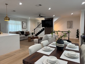A modern living room with a sofa, coffee table, and dining area with a set table.