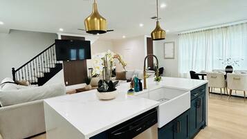 A modern kitchen with a central island, built-in dishwasher, and pendant lighting.