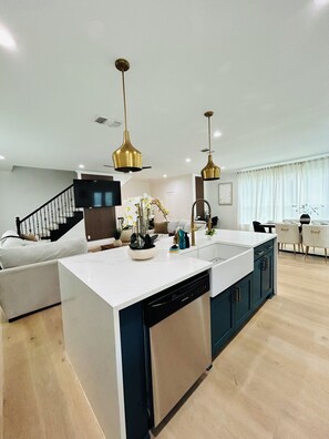 Una cocina moderna con una isla central, lavavajillas integrado e iluminación colgante.