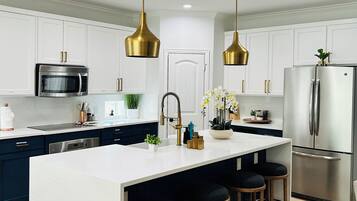 A modern kitchen with a central island, stainless steel appliances, and gold pendant lighting.