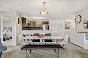 A modern kitchen with white cabinets, a stainless steel refrigerator, and a dining area with a white table and chairs. - Daybreak | Outdoor Pool | Hot Tub | Gym | Balcony (Invermere)