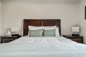 A hotel room with a large bed, two bedside tables, and a wooden headboard. - Daybreak | Outdoor Pool | Hot Tub | Gym | Balcony (Invermere)