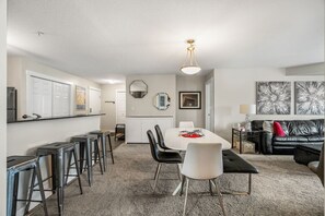 A modern living room with a dining area, a black leather sofa, and a coffee table. - Daybreak | Outdoor Pool | Hot Tub | Gym | Balcony (Invermere)