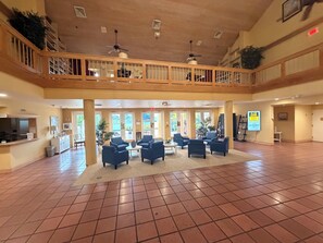 Eine geräumige Lobby mit hoher Decke, mehreren Sitzbereichen und einem Balkon mit Blick ins Innere.
