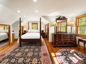 Une chambre spacieuse avec un lit à baldaquin, une commode en bois et un grand miroir.