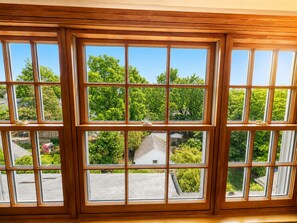 A window with multiple panes, offering a view of a residential area with trees and houses. - Luxury Furnished Executive Residence 5 bedroom in Chevy Chase near Lafayette (Washington)