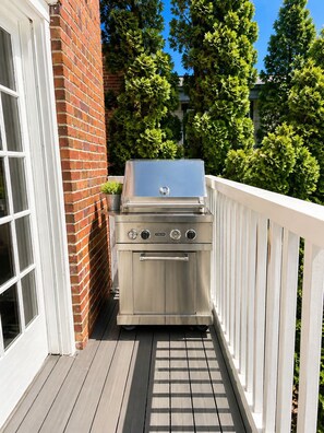A stainless steel Viking grill on a wooden deck with a white railing, adjacent to a brick wall and a window. - Luxury Furnished Executive Residence 5 bedroom in Chevy Chase near Lafayette (Washington)