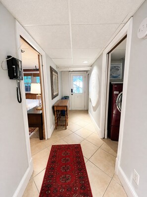 A hallway with a red patterned rug, a wooden table, a telephone, and a washing machine. - Luxury Furnished Executive Residence 5 bedroom in Chevy Chase near Lafayette (Washington)