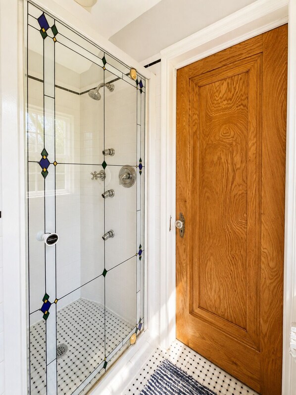 Une douche avec une porte en verre et une porte en bois à côté.