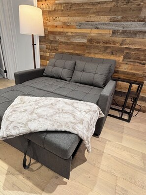 Une pièce moderne avec un canapé gris, un plaid à motifs et un mur en bois.