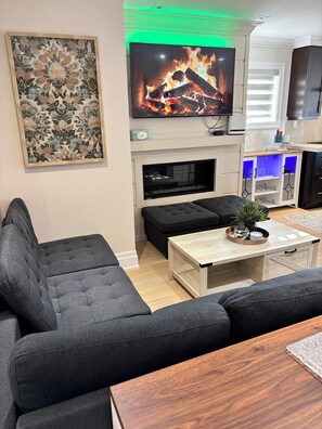 A living room with a flat-screen TV, a fireplace, a sofa, and a coffee table. - 3 bedroom 2 bath I 1 min walk to beach (Georgina)