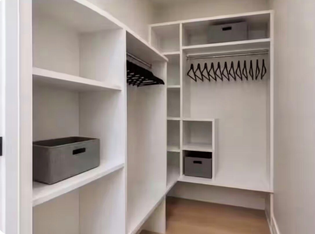 A white closet with multiple shelves and hanging space.