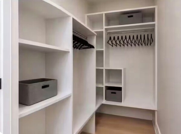 Un placard blanc avec plusieurs étagères et un espace pour suspendre les vêtements.