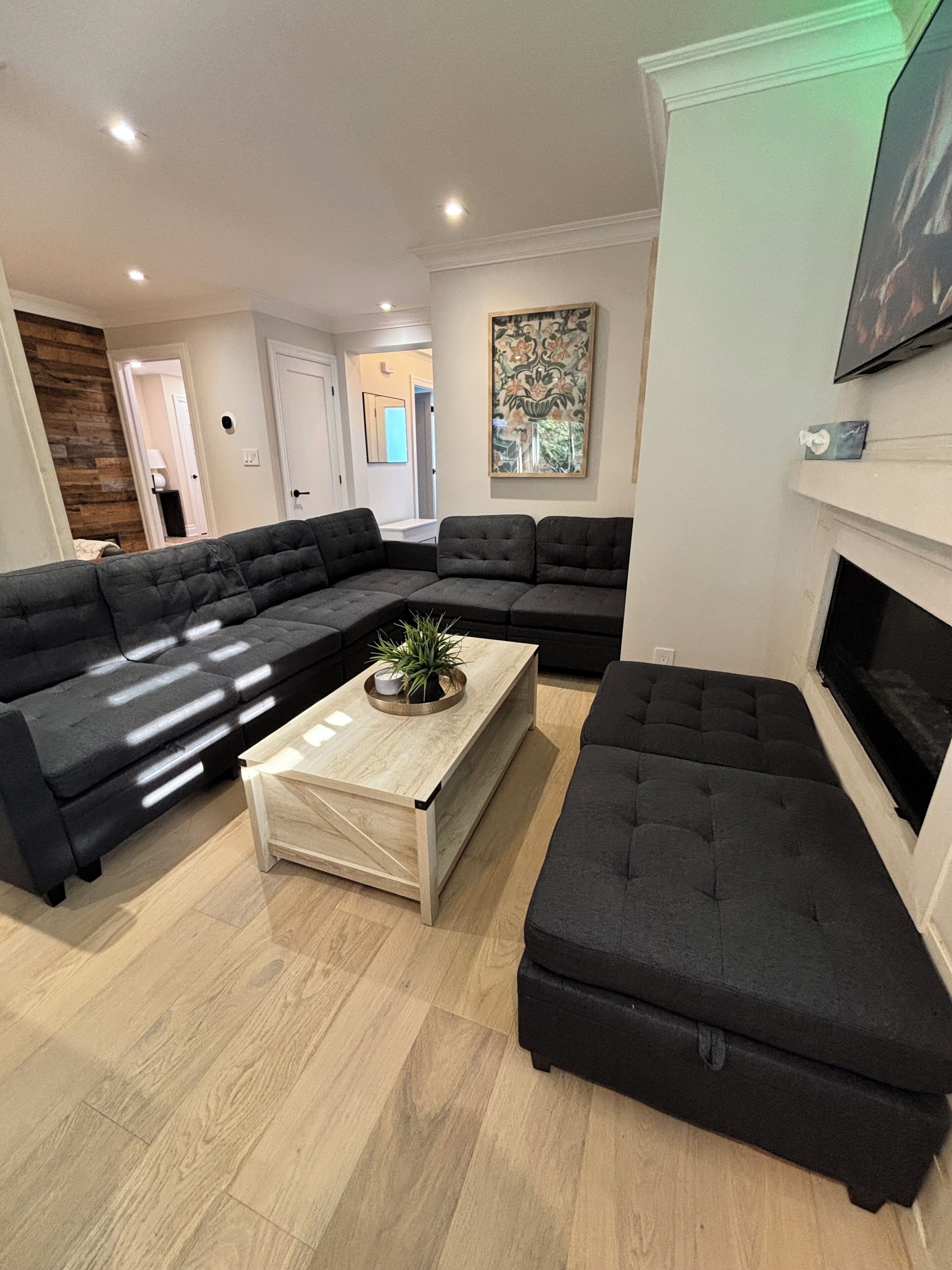 Un salon moderne avec un canapé d’angle, une table basse et une cheminée.