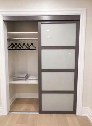 Ein begehbarer Kleiderschrank mit Schiebetür, Regalen und einer Kleiderstange.