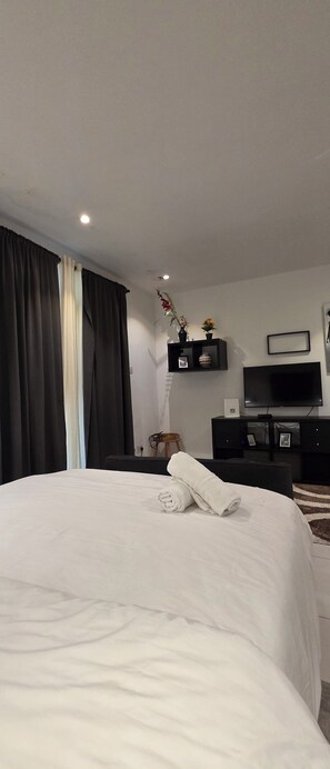 Ein Hotelzimmer mit einem Bett, einem Fernseher, einem Schreibtisch und einem Fenster mit Vorhängen.
