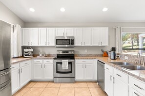 A modern kitchen with white cabinets, stainless steel appliances, and a granite countertop.