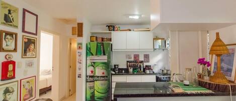A compact kitchen with white cabinets, a refrigerator, and a small dining area with a table and chairs.