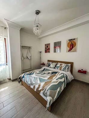 Ein Schlafzimmer mit Bett, einer Pendelleuchte, einem Handtuchhalter und Wandbildern.