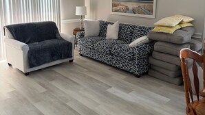 Un salon avec un canapé, un fauteuil, une lampe et un ventilateur de plafond.