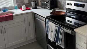 Une cuisine moderne avec des meubles blancs, un four à micro-ondes en acier inoxydable, un grille-pain et une cuisinière.