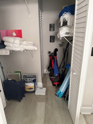 Ein kleines Zimmer mit einem Bett, einem Regal mit gefalteten Handtüchern, einem Heizkörper, einem Koffer und einer blauen Matte.