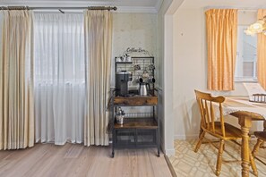 A room with a coffee station, a wooden chair, and curtains.